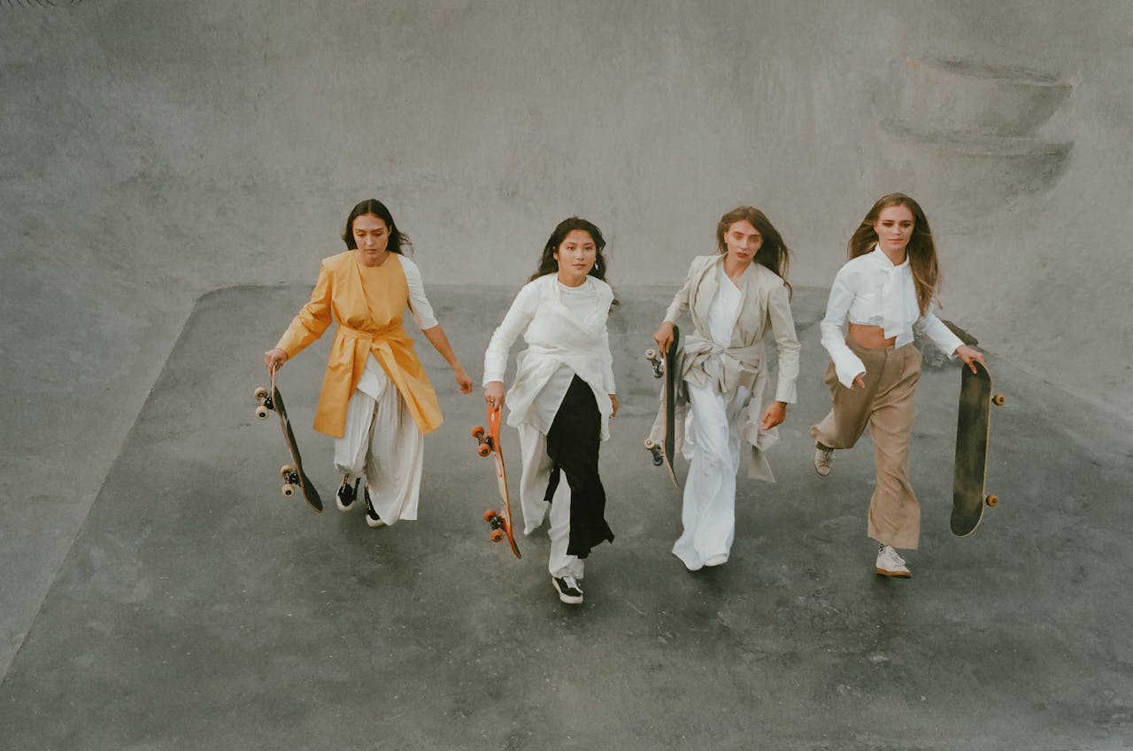 Four stylish women walking with skateboards in an urban skate park, showcasing empowerment and fashion.